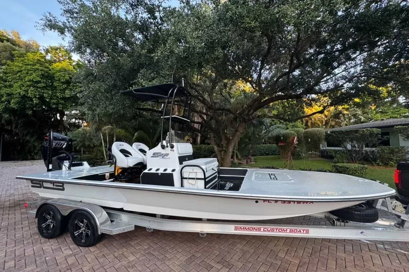 Slide: The Image of 2023 SCB S22 boat on trailer, parked in a lush, tree-lined driveway. - 0
