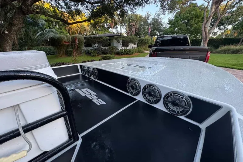 Slide: The Image of 2023 SCB S22 boat with speakers, parked near a truck in a lush garden setting. - 3