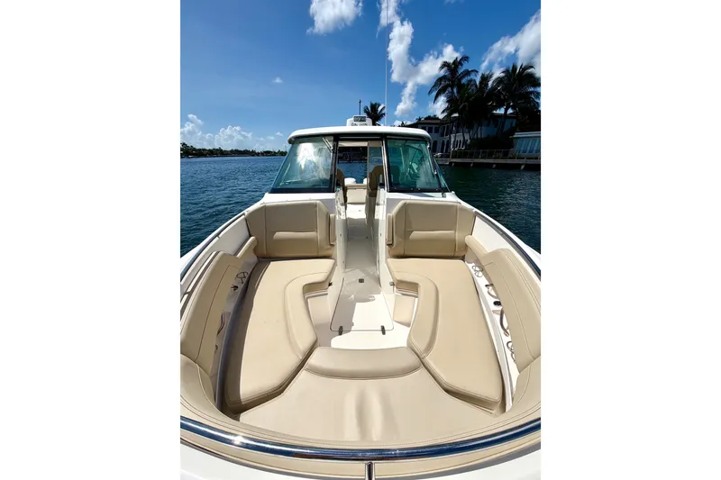 Slide: The Image of 2017 Pursuit DC 325 Dual Console boat with spacious seating, docked by palm trees. - 25