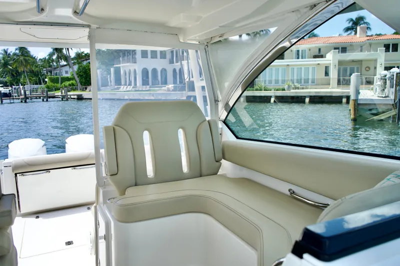 Slide: The Image of 2017 Pursuit DC 325 Dual Console interior with beige seating, overlooking waterfront homes. - 15