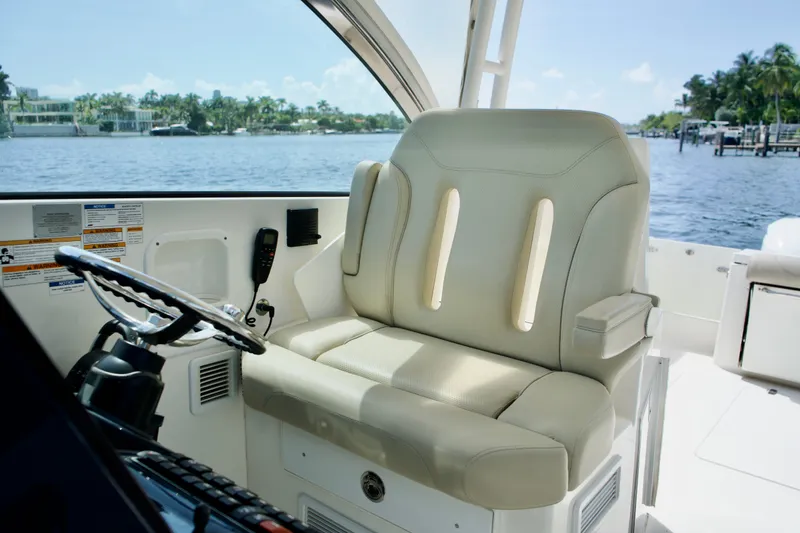 Slide: The Image of Captain's seat on 2017 Pursuit DC 325 Dual Console boat, overlooking serene waterfront. - 16