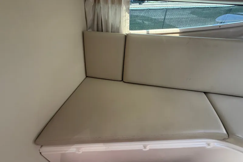 Slide: The Image of Interior seating of 2018 Regal 28 Express boat, featuring beige cushions and window view. - 73