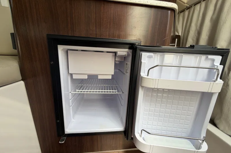 Slide: The Image of Open mini fridge inside 2018 Regal 28 Express boat, featuring wooden cabinetry. - 63