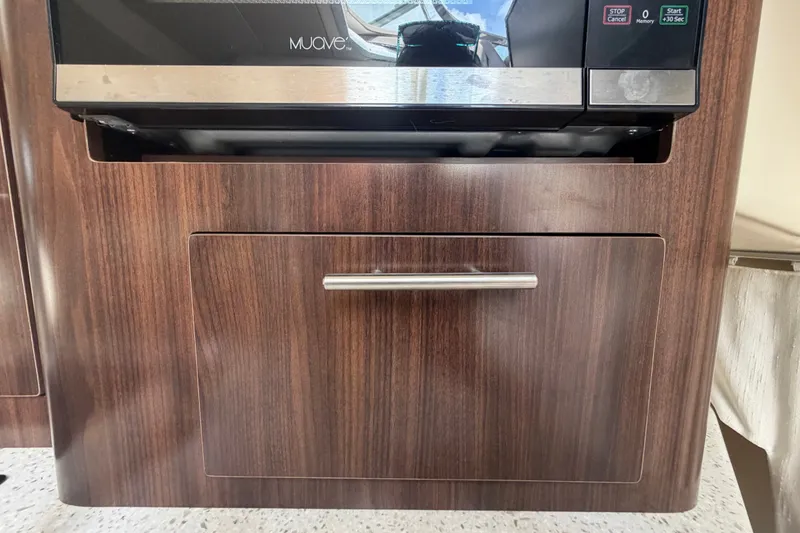 Slide: The Image of Wooden cabinet with a microwave in a 2018 Regal 28 Express boat interior. - 67