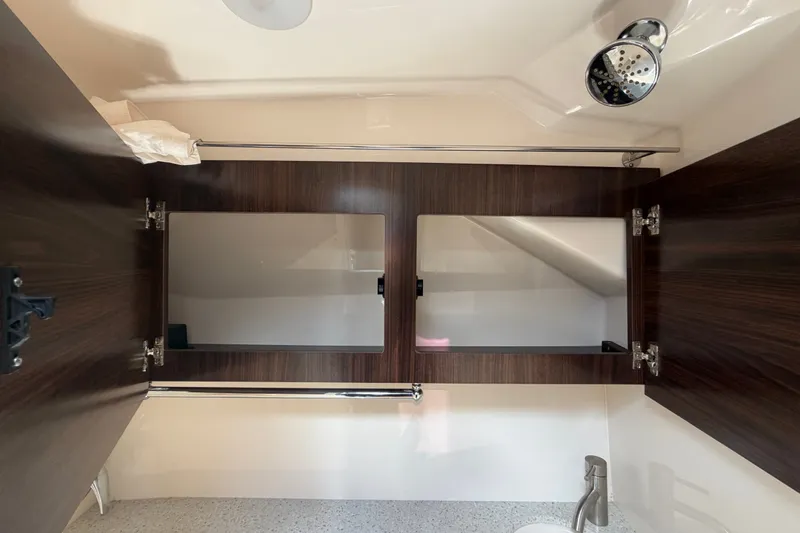 Slide: The Image of Bathroom interior of 2018 Regal 28 Express boat with mirrored cabinets and showerhead. - 90