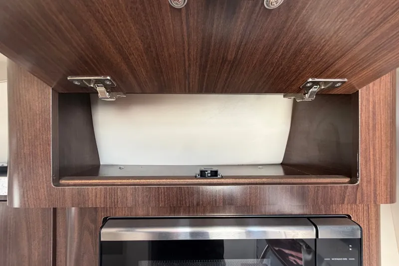 Slide: The Image of Open wooden cabinet above microwave in 2018 Regal 28 Express boat interior. - 66