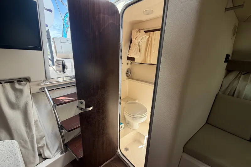 Slide: The Image of Interior of 2018 Regal 28 Express boat showing compact bathroom and seating area. - 87