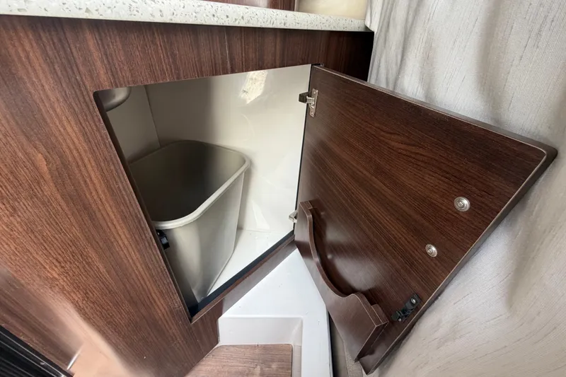 Slide: The Image of 2018 Regal 28 Express interior cabinet with trash bin, wood finish. - 61