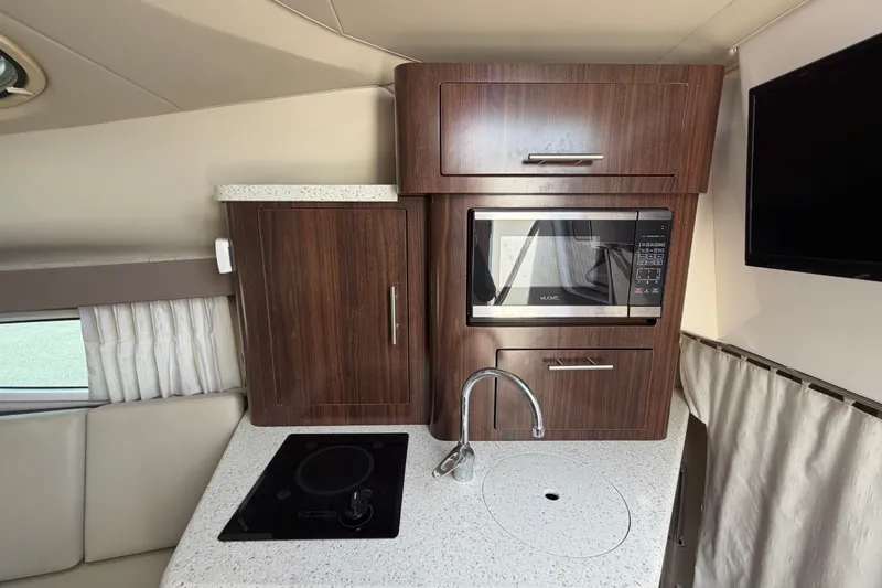 Slide: The Image of 2018 Regal 28 Express boat interior kitchen with microwave, stove, and sink. - 64