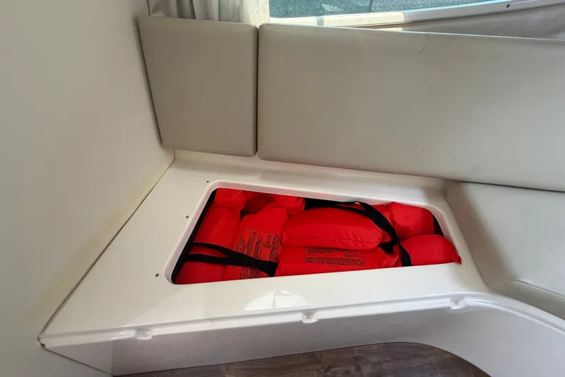 Slide: The Image of Storage compartment with red life jackets on a 2018 Regal 28 Express boat. - 74
