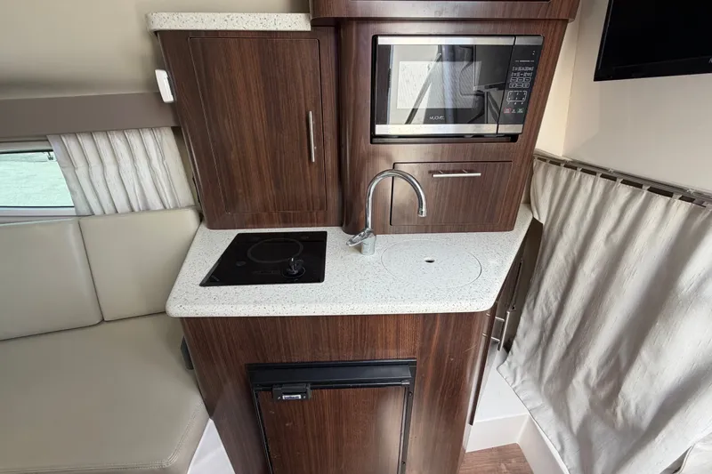 Slide: The Image of Compact kitchen area in a 2018 Regal 28 Express boat with microwave and stovetop. - 59