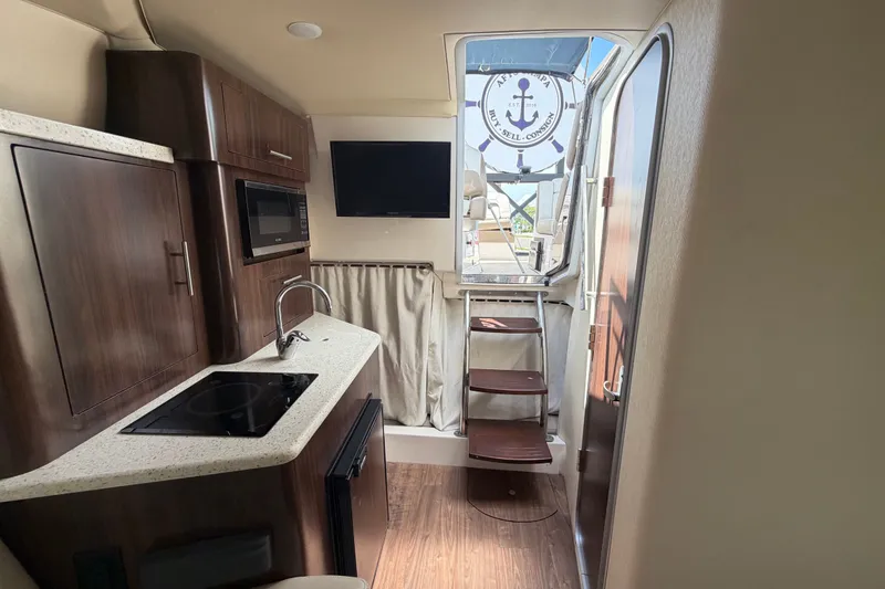 Slide: The Image of Interior of a 2018 Regal 28 Express boat featuring a compact kitchen and modern amenities. - 84