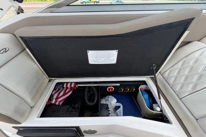 Slide: The Image of Open storage compartment in a 2018 Regal 28 Express boat, featuring various items and controls. - 29