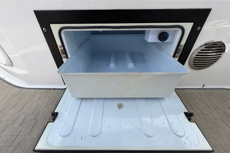 Slide: The Image of Open cooler compartment on 2018 Regal 28 Express boat, showing interior storage space. - 27