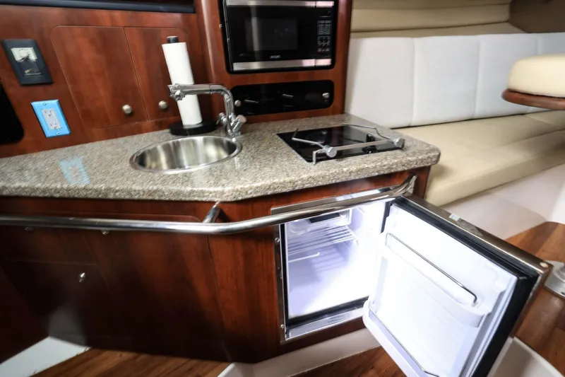 Slide: The Image of 2018 Robalo R305 Walkaround interior with kitchenette, featuring sink, stove, and open fridge. - 32