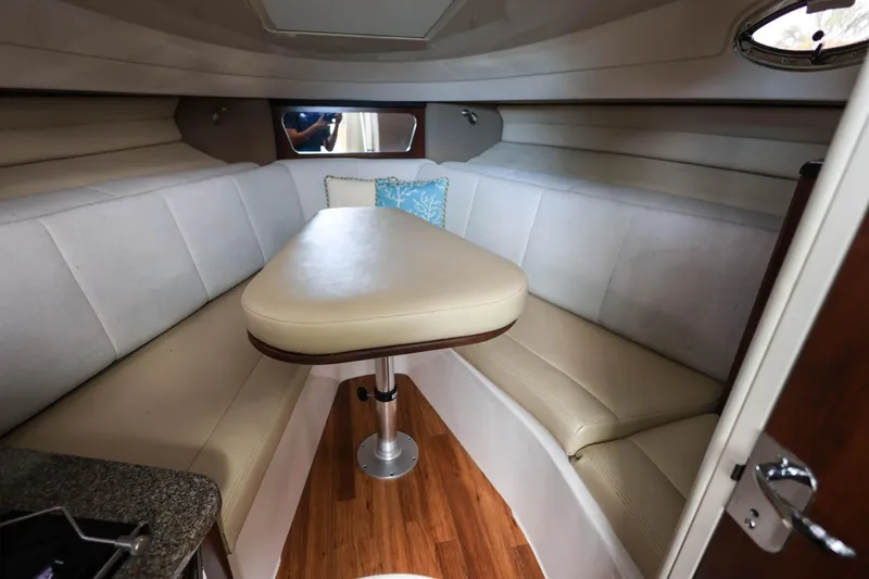 Slide: The Image of 2018 Robalo R305 Walkaround cabin interior with cushioned seating and wooden flooring. - 26