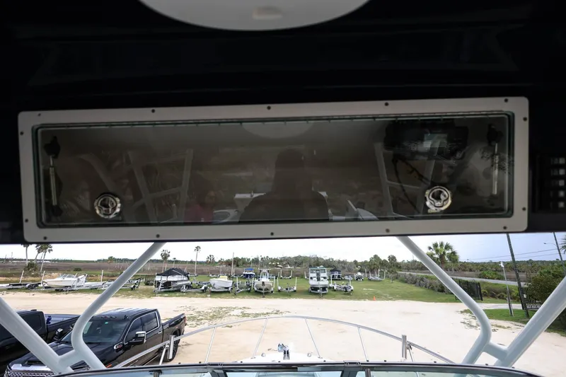 Slide: The Image of 2018 Robalo R305 Walkaround boat interior with windshield view of parked vehicles. - 35