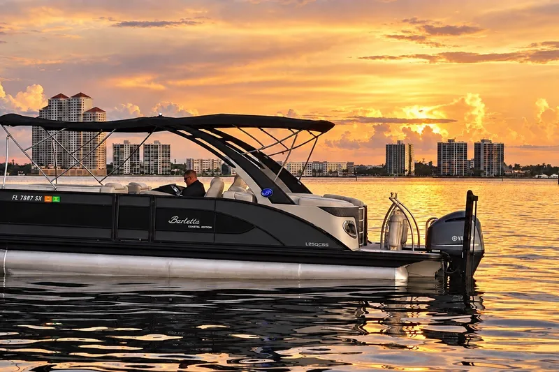 Slide: The Image of 2020 Barletta L-CLASS L25QCSSA boat on water at sunset, city skyline in background. - 15
