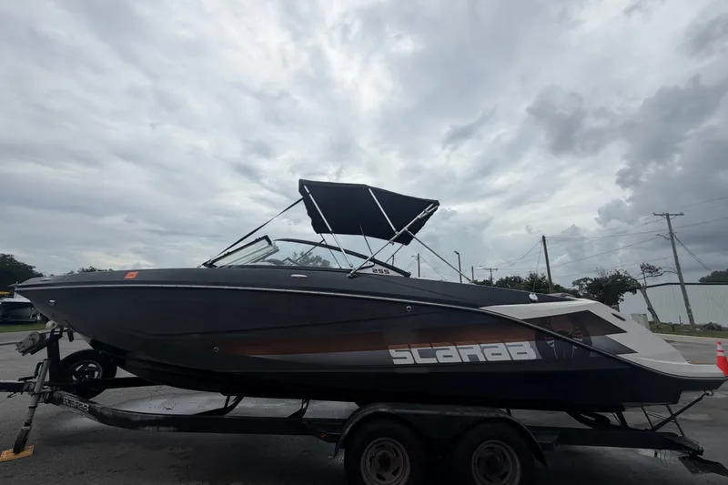Slide: The Image of Scarab 255 ID 2018 con scafo nero e bimini top su rimorchio, cielo nuvoloso. - 7