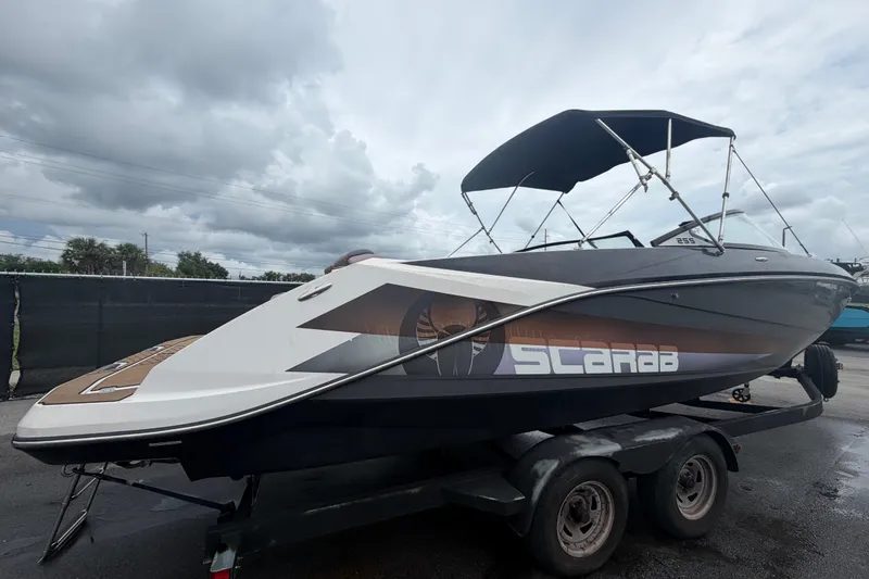 Slide: The Image of 2018 Scarab 255 ID boat on trailer under cloudy sky. - 2