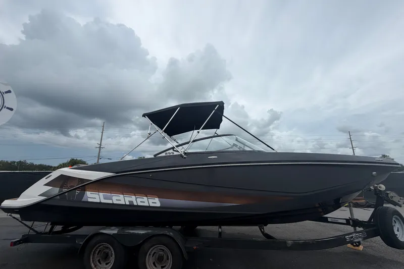 Slide: The Image of 2018 Scarab 255 ID boat on trailer under cloudy sky. - 1