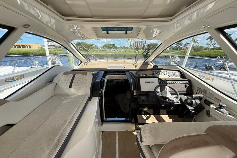 Slide: The Image of 2018 Sea Ray Sundancer 350 Coupe cockpit with modern controls and seating, docked by water. - 22