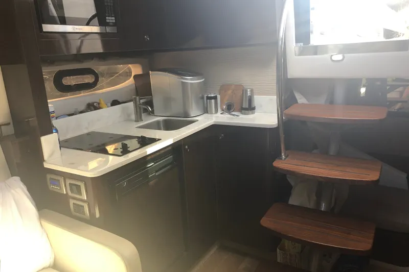 Slide: The Image of 2018 Sea Ray Sundancer 350 Coupe interior kitchen with modern appliances and wooden stairs. - 14