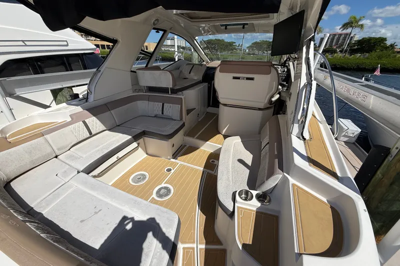 Slide: The Image of 2018 Sea Ray Sundancer 350 Coupe interior with seating and helm, docked by water. - 17