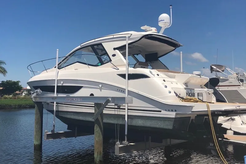The Image of 2018 Sea Ray Sundancer 350 Coupe yacht docked on a lift under clear blue skies. - 0