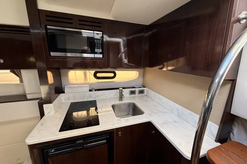 Slide: The Image of 2018 Sea Ray Sundancer 350 Coupe kitchen with microwave, stove, and sink. - 34