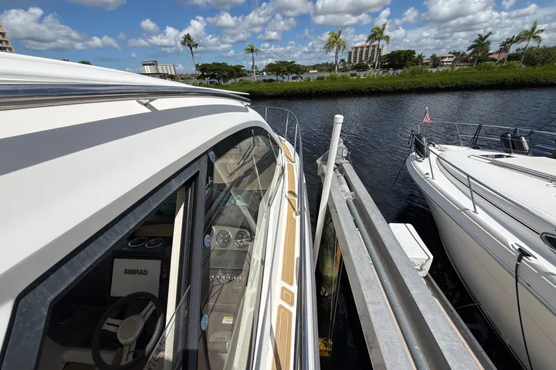 Slide: The Image of 2018 Sea Ray Sundancer 350 Coupe docked beside another boat, under a partly cloudy sky. - 102