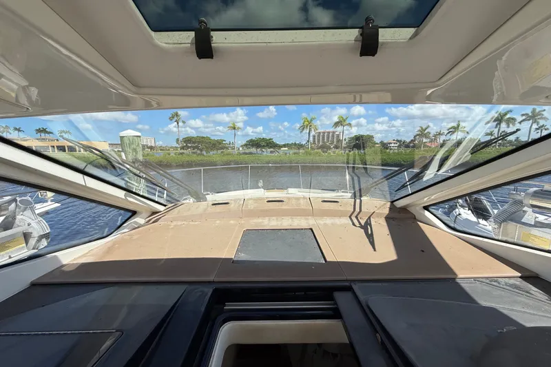 Slide: The Image of 2018 Sea Ray Sundancer 350 Coupe cockpit view with waterfront and palm trees. - 30