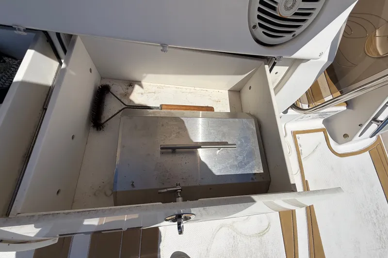 Slide: The Image of Storage compartment on 2018 Sea Ray Sundancer 350 Coupe with cleaning brush and metal cover. - 127