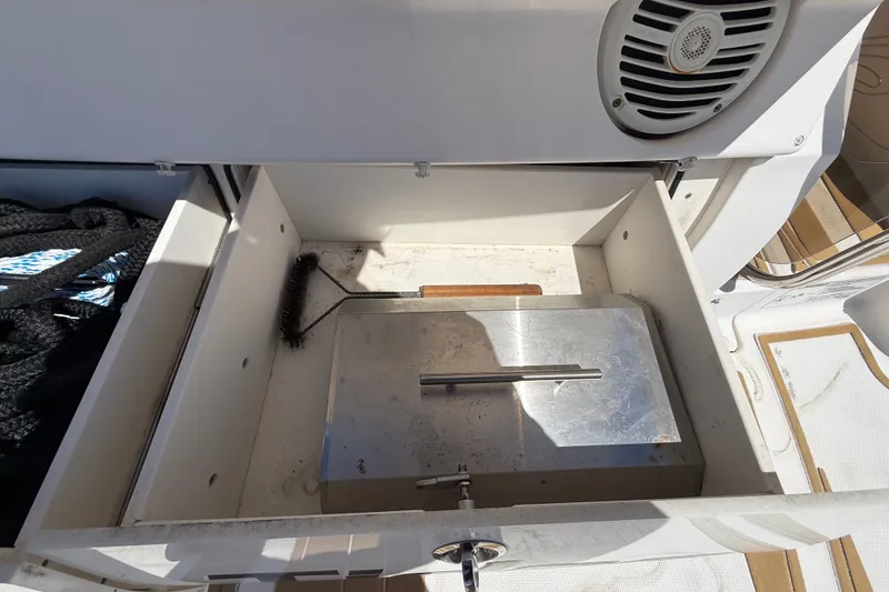 Slide: The Image of Open storage compartment on 2018 Sea Ray Sundancer 350 Coupe boat, featuring a brush and speaker. - 126