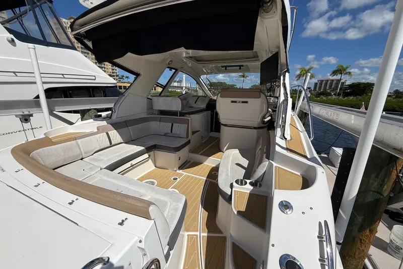 Slide: The Image of 2018 Sea Ray Sundancer 350 Coupe interior with seating and helm, docked under blue sky. - 16