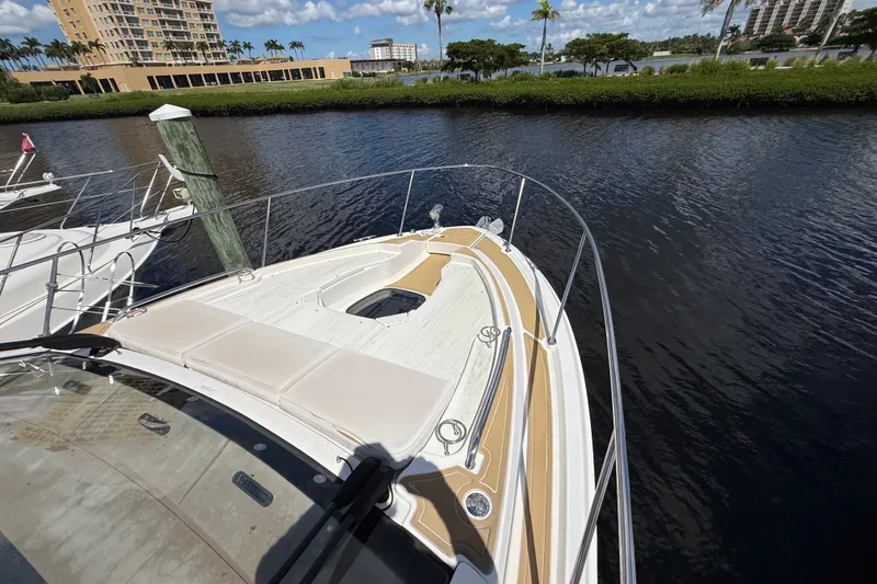 Slide: The Image of 2018 Sea Ray Sundancer 350 Coupe docked by waterfront buildings and lush greenery. - 105