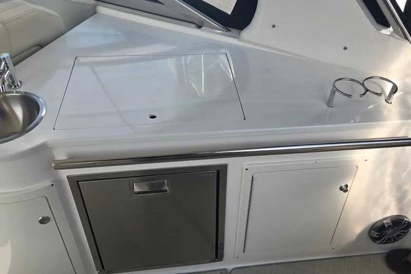 Slide: The Image of 2022 Regal 33 Express yacht kitchenette with sink, storage, and cup holders. - 18