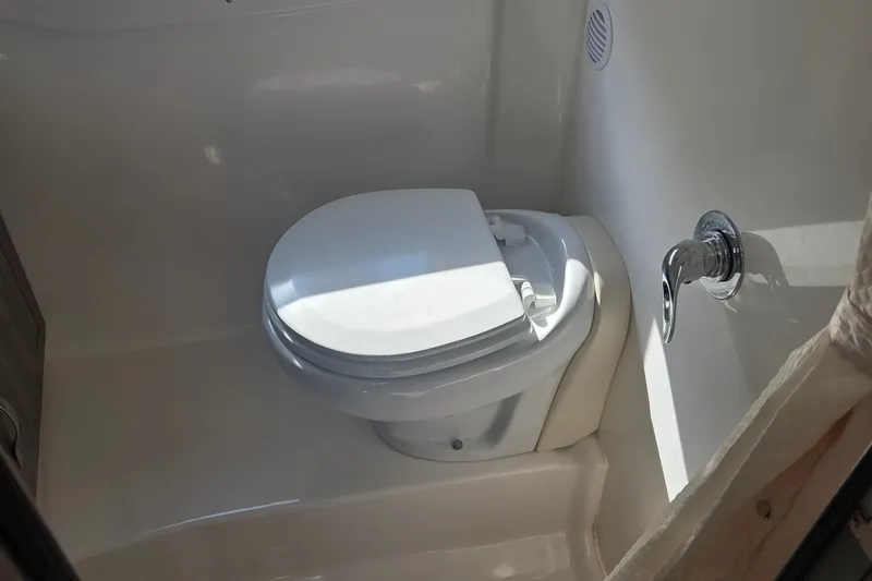 Slide: The Image of 2022 Regal 33 Express boat bathroom with compact toilet and chrome flush handle. - 26