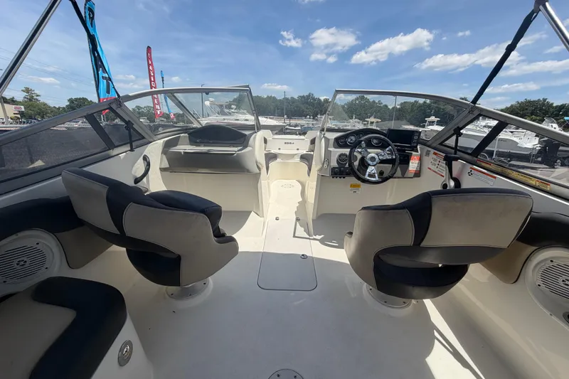 Slide: The Image of 2018 Stingray 204 LR boat interior with steering wheel, seating, and dashboard under a clear sky. - 14
