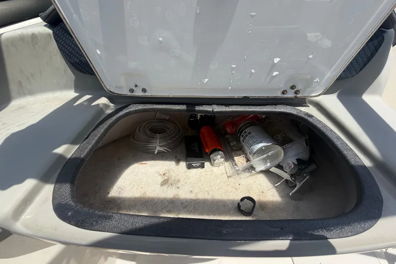 Slide: The Image of Open storage compartment in a 2018 Stingray 204 LR boat with various items inside. - 23
