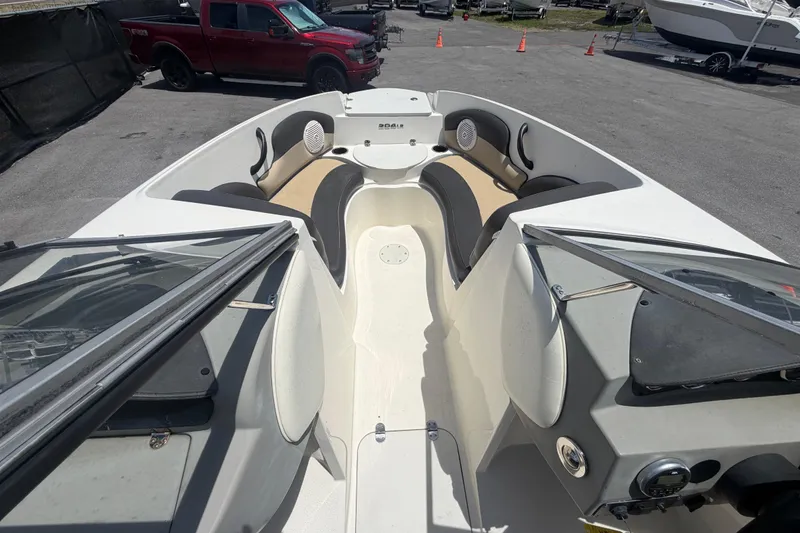 Slide: The Image of 2018 Stingray 204 LR boat interior with seating and dashboard, parked near a red truck. - 28