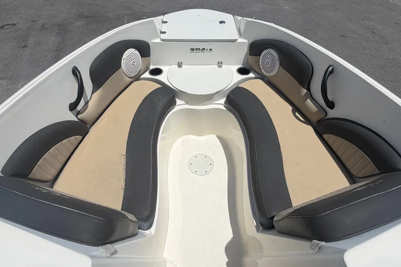 Slide: The Image of 2018 Stingray 204 LR boat interior with beige and black seating, cup holders, and speakers. - 29