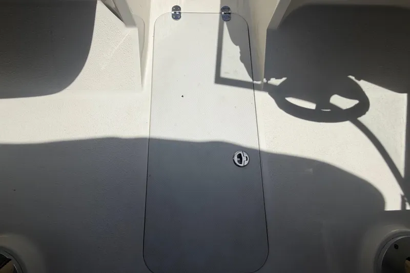 Slide: The Image of 2018 Stingray 204 LR boat deck with storage hatch and steering wheel shadow. - 26
