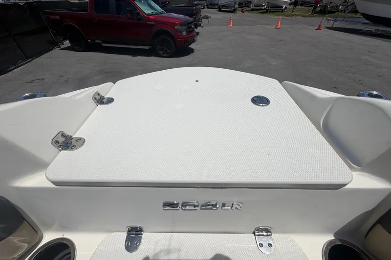 Slide: The Image of 2018 Stingray 204 LR boat rear view with storage hatch and red truck in background. - 34