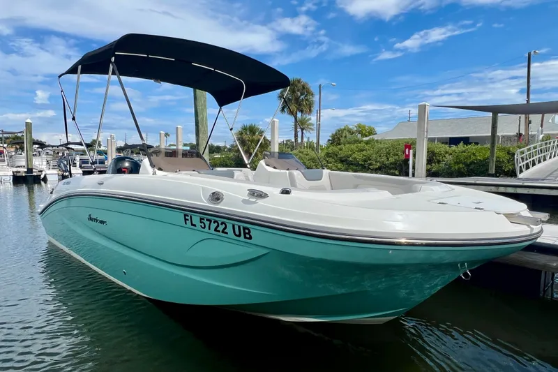 Slide: The Image of 2026 Hurricane SunDeck Sport 2050 OB boat docked, featuring a sleek design and canopy. - 2