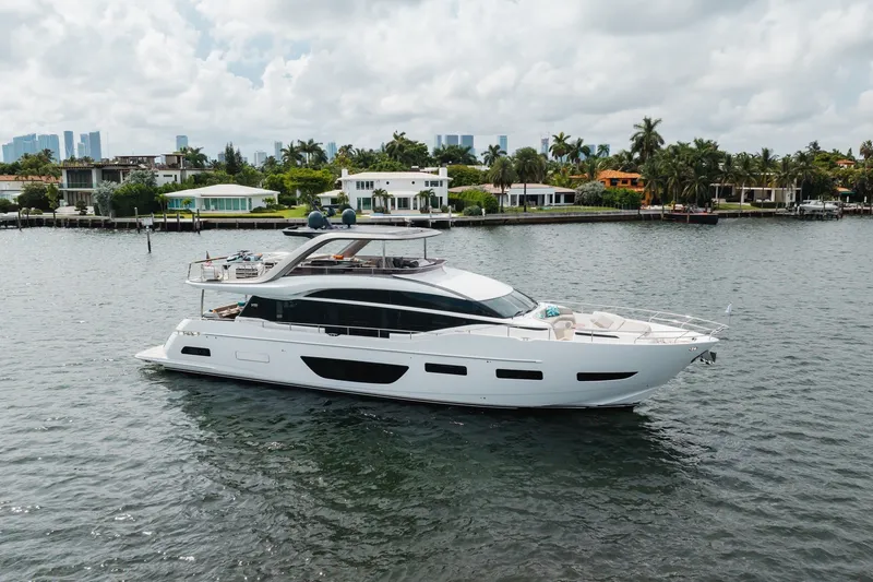 Slide: The Image of Luxurious 2021 Princess Y85 yacht cruising near waterfront homes under cloudy skies. - 6