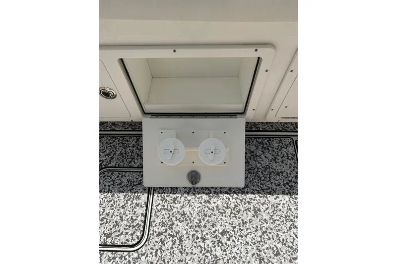 Slide: The Image of 2018 World Cat 320 CC boat compartment with dual circular controls on speckled flooring. - 27