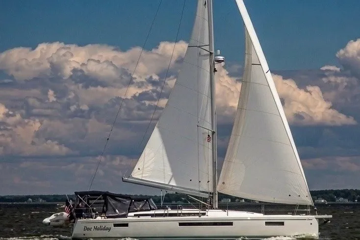 The Image of A 2020 Jeanneau Sun Odyssey 490 sailing on open water under a cloudy sky. - 0