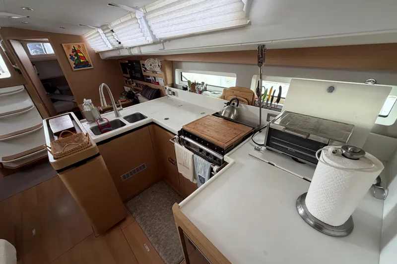 Slide: The Image of Interior of 2020 Jeanneau Sun Odyssey 490 yacht, featuring a modern kitchen with wooden cabinetry. - 18