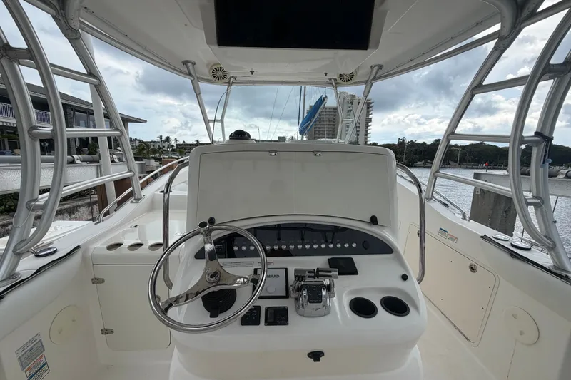 Slide: The Image of 2007 Boston Whaler 320 Outrage helm with steering wheel and controls, docked by waterfront. - 25